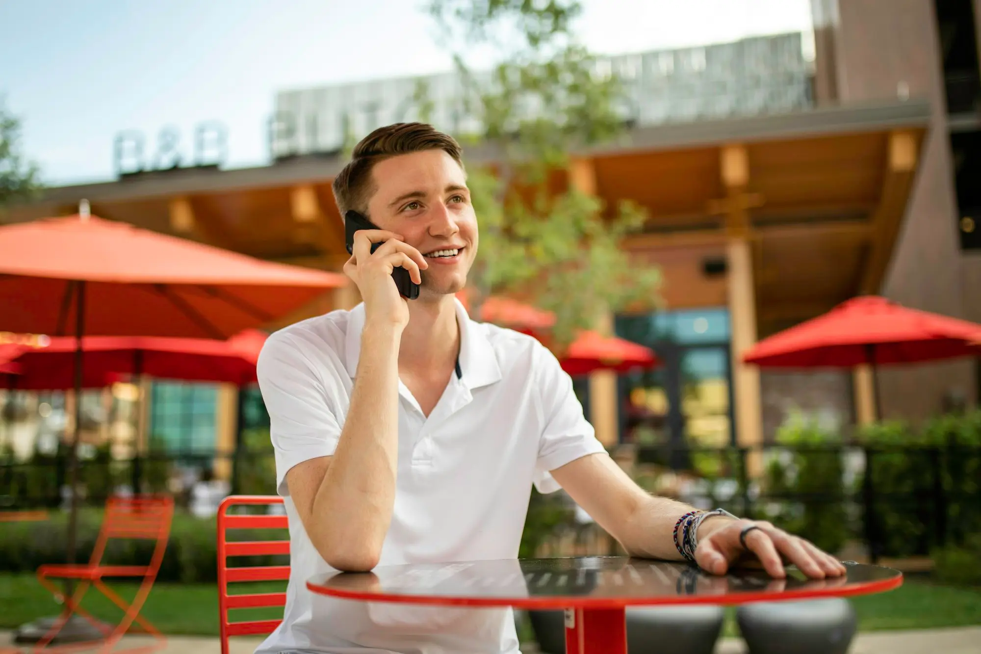 Business owner on a phone call at an outdoor café table, checking in with a co-account holder about approving data sharing